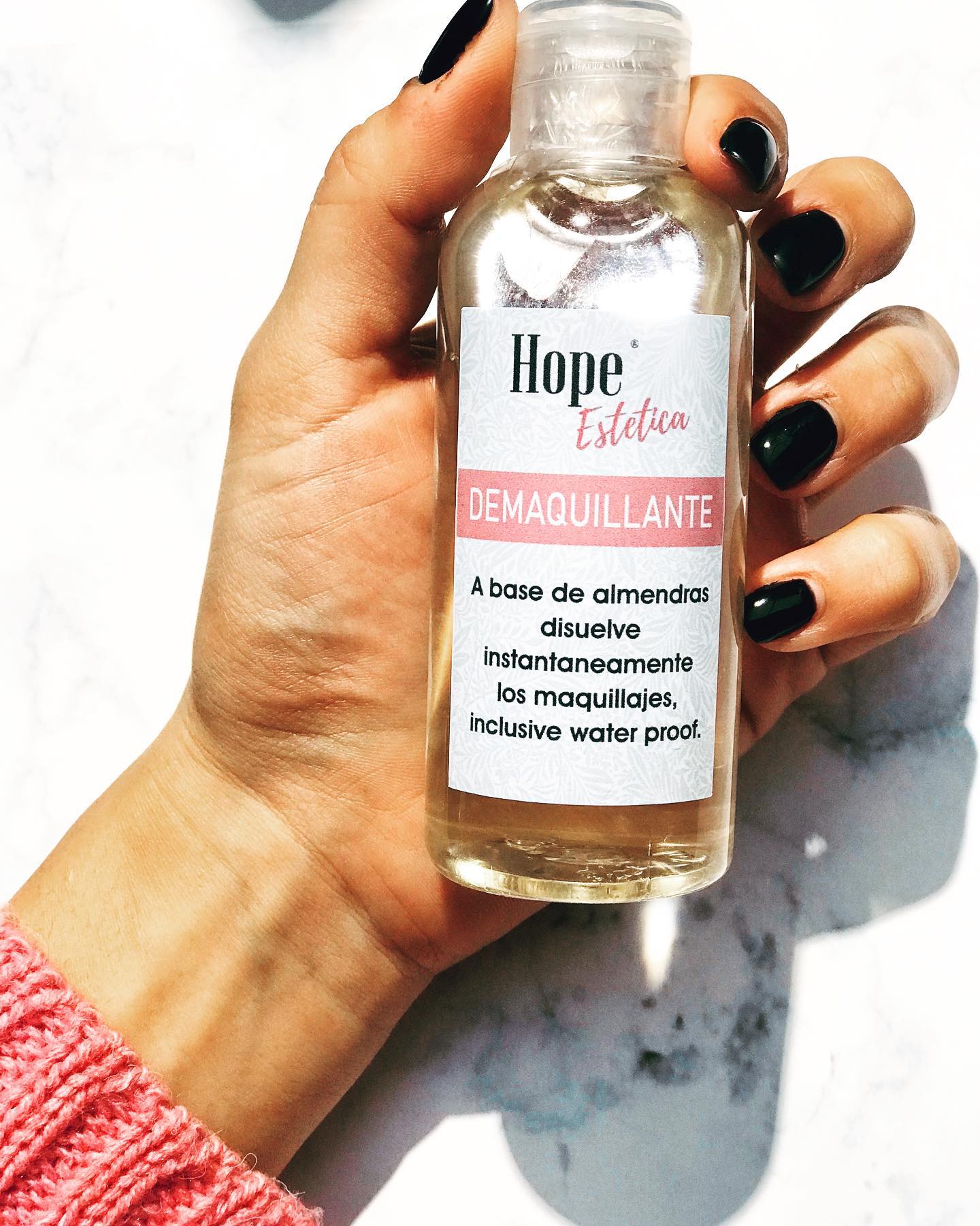 Una mano sostiene el demaquillante a base de almendras de la línea Hope Estética